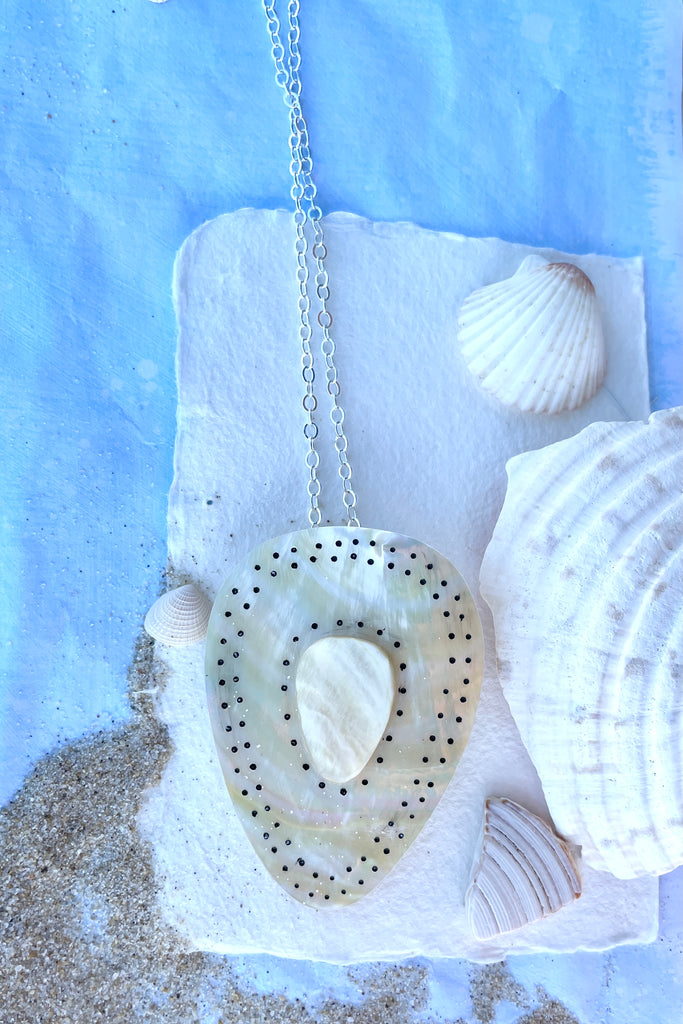 Beautiful golden Mother of Pearl shell pendant cut into a strong tribal shape, it has inlaid spots that give it the feeling of strength