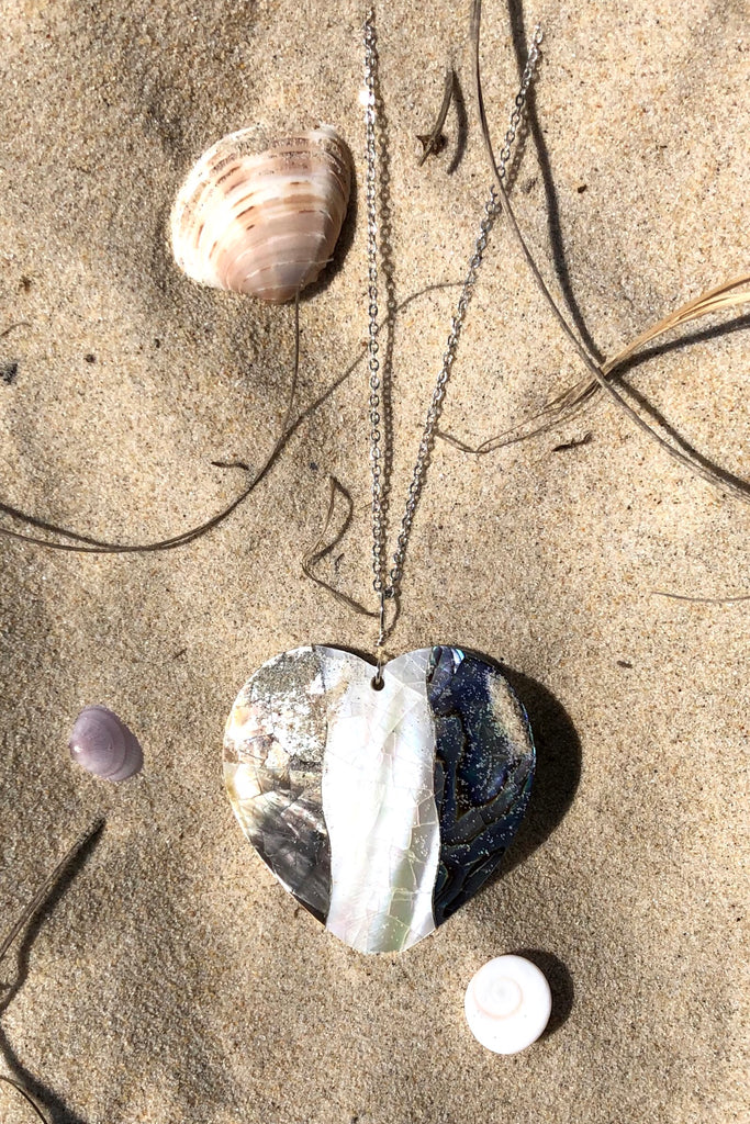 A charming heart shaped pendant, the surface is silvery grey blue and pearly white mother of pearl shell that has been applied to a base of shell,