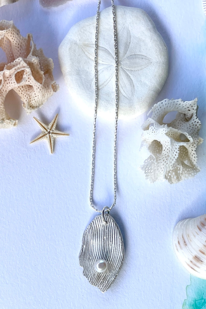 The pendant is solid silver, it is cast from the surface of a Pippi shell, and designed to carry the pearl bubble on the waves reaching the shore.
