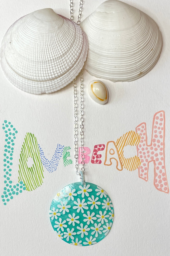 sweetheart daisy necklace is a Capiz shell circle hand painted with 60's style daisies