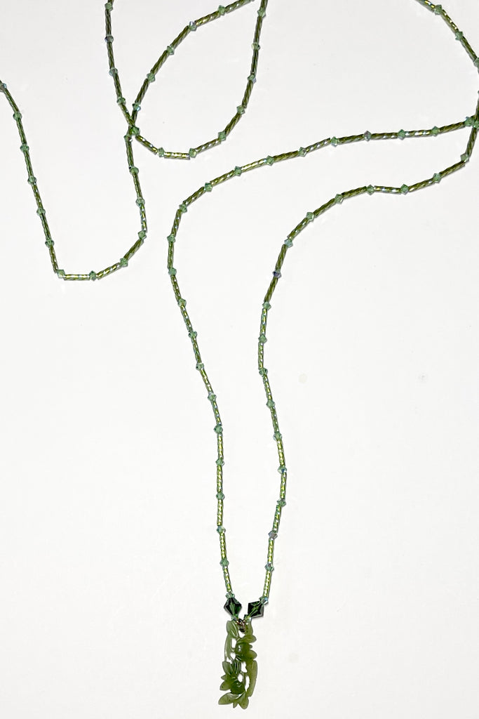 necklace is opera length and can be worn long or doubled to be shorter. Crystal glass bugle beads and green Swarovski crystals. The centre is a pendant of beautifully carved foliage in greenstone jade.