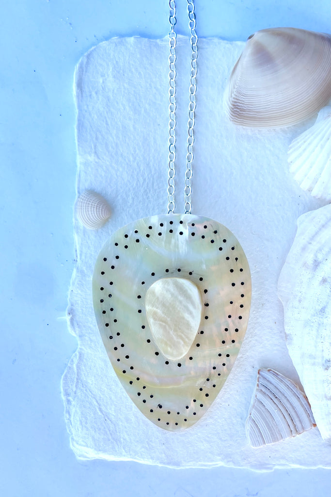 Beautiful golden Mother of Pearl shell pendant cut into a strong tribal shape, it has inlaid spots that give it the feeling of strength