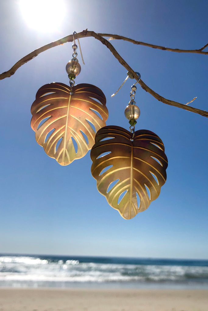 The gorgeous leaf in gold and silvery bronze Mother of Pearl has been hand cut and polished. At the top there is an iridescent crystal bead and a swarovski crystal bead. These earrings are made exclusively for Mombasa Rose