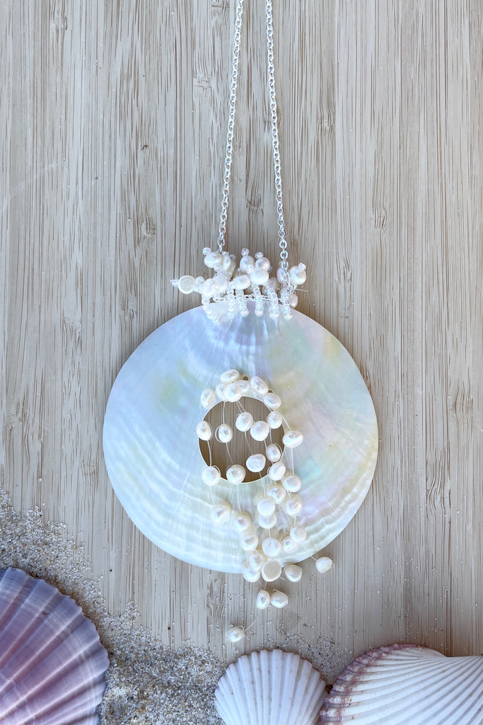 An iridescent circle of beautiful golden Mother of Pearl shell, hung with pearls on a simple silvery chain.