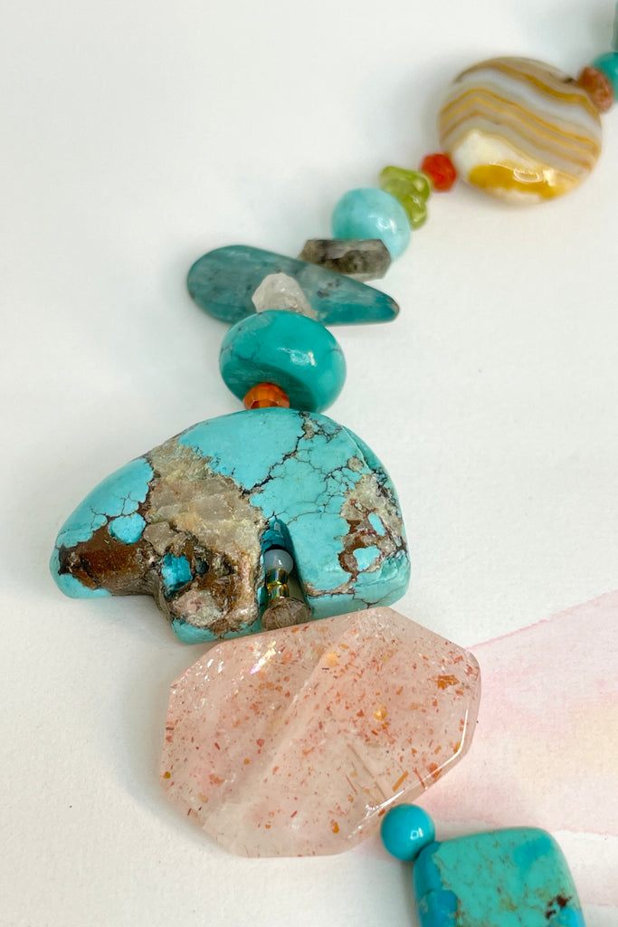 The necklace features a hand carved Zuni bears bought in Taos new Mexico. Stones are Natural Turquoise, Herkimer Diamond, Kyanite rough shards, Pearl, natural Sunstone, Strawberry Quartz, Banded Agate, Peridot and Labradorite .