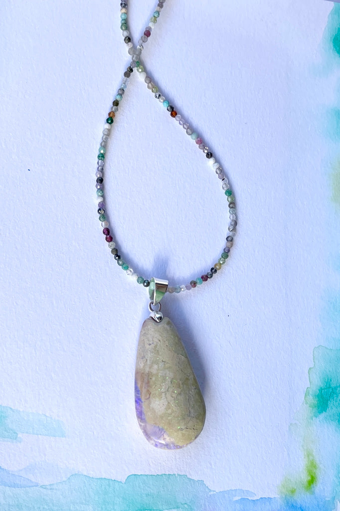 This opal is a one off piece, a hand cut and shaped light matrix opal, there is a lovely pale mauve crystal cave on one side, the top surface shows a mysterious bright green sparkle under sunlight.