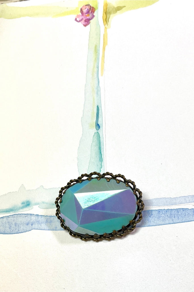 An old and unusual brooch, most likely from the 1930's. The blue is a coated glass the edge is metal