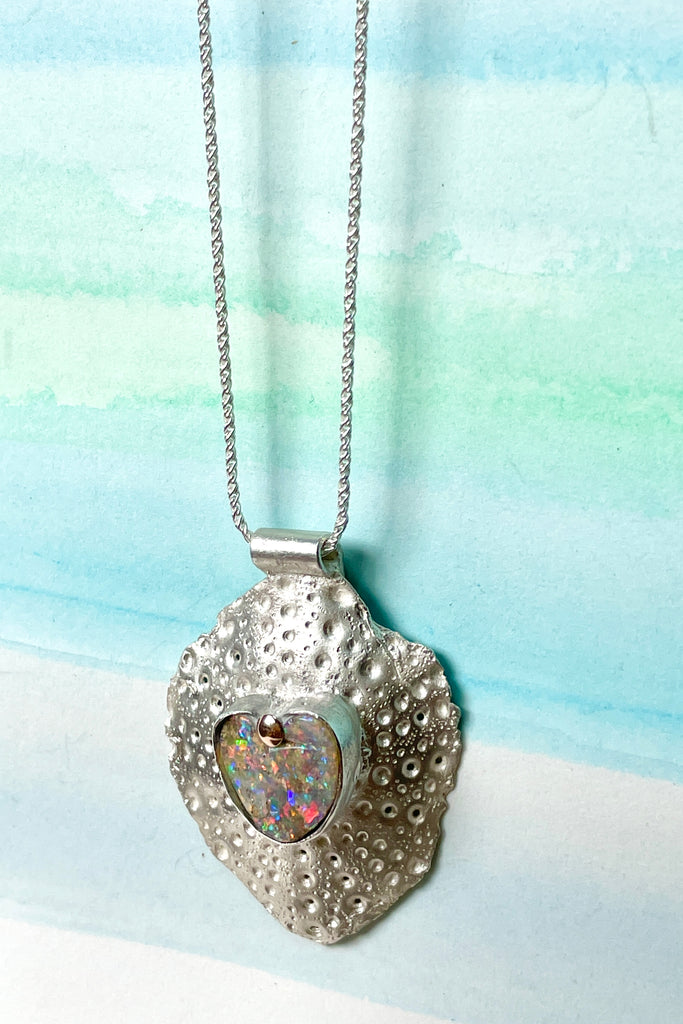 The heart opal centre piece is cut from natural solid Australian Opal. The silver is moulded from the shell of a sea urchin, then the opal is applied with the aid of a small gold dot of repurposed 18ctgold.