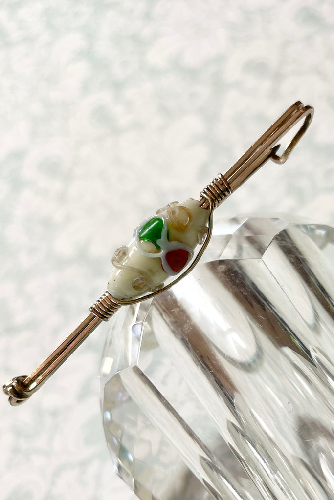 An interesting vintage tie pin with gold wire work around a white lamp work bead. 