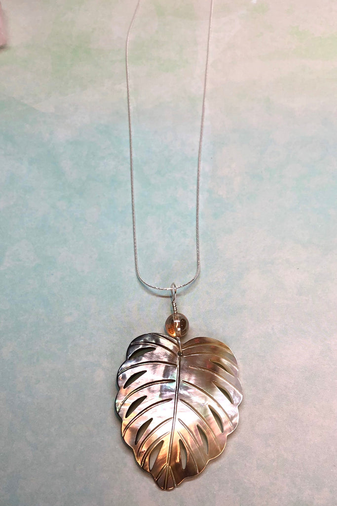 The gorgeous leaf pendant in gold and silvery bronze Mother of Pearl has been hand cut and polished. At the top there is an iridescent crystal bead.