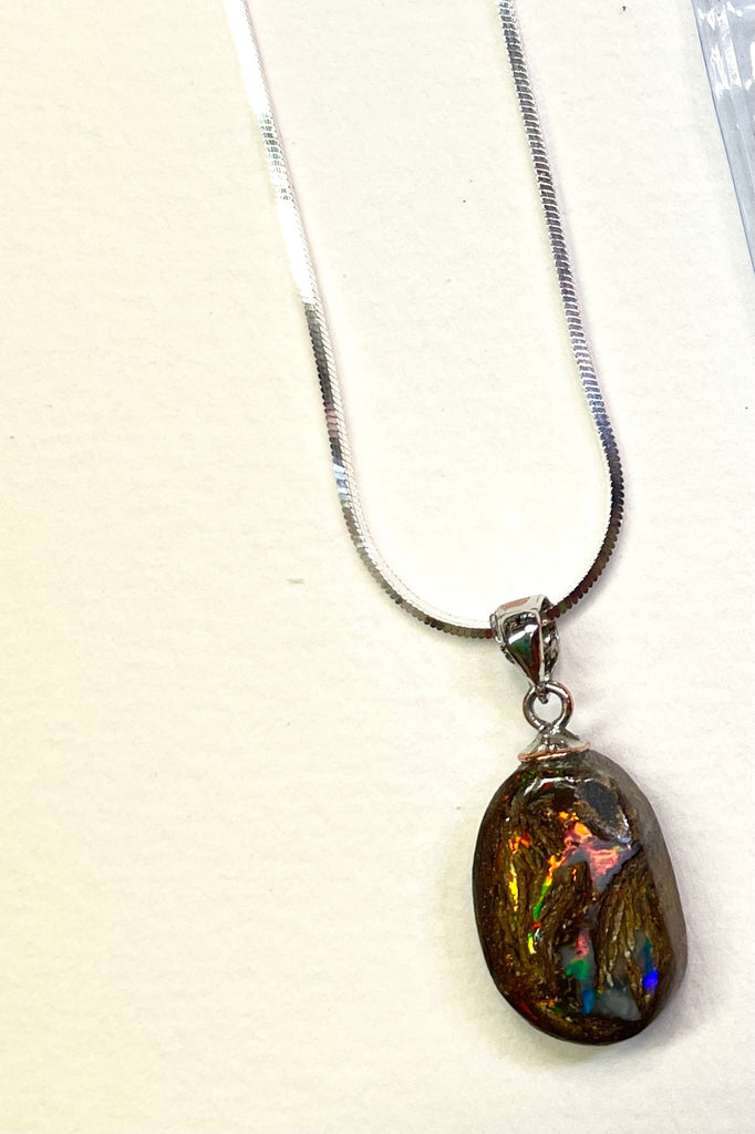 This opal has a lovely flashes of colour across the centre of the stone, predominately red and pink but with green and yellow as well. It is cut into a rounded oval and shows the mark of the artist who cut and polished the stone. This genuine Australian Boulder Opal stone was cut and polished in Queensland by an Opal miner.