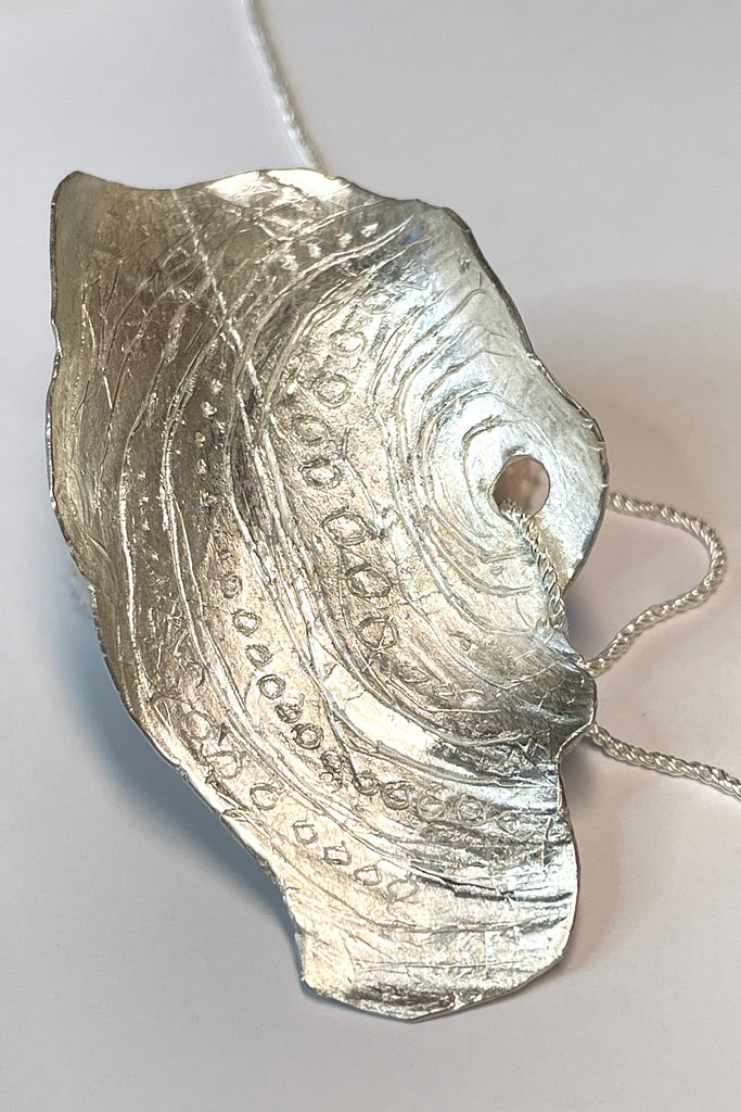 The centre piece is solid silver, it is a cast from a shell found on the Noosa North Shore. The necklace is just so special, the design is original as it is cast directly from the shell. The back of the piece is beautifully inscribed with a pattern of bubbles and waves.