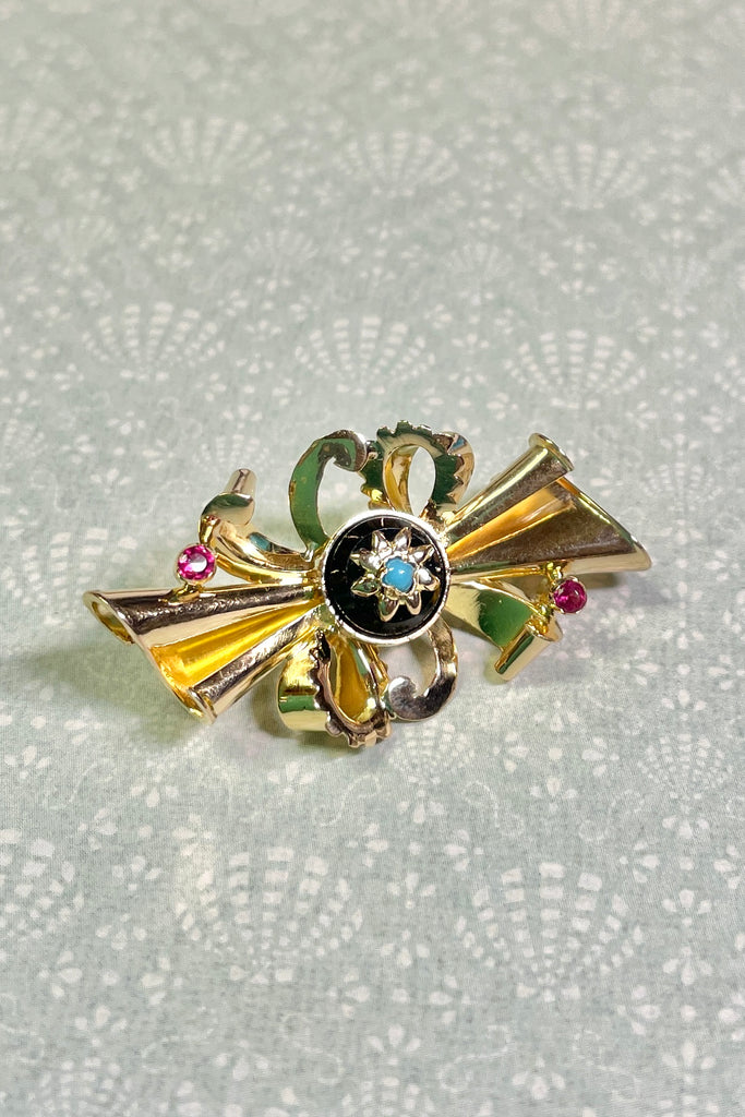 the brooch is unmarked gold with two tiny pink stones either pink garnet or ruby, the centre is black onyx with a star that has a turquoise centre stone.