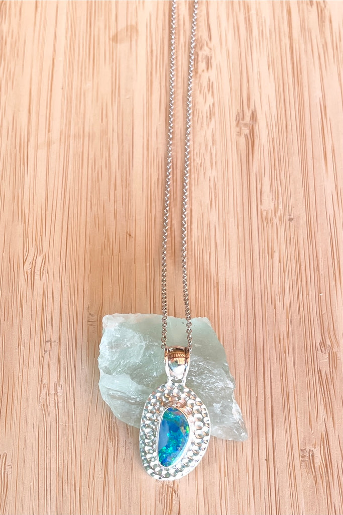 The Australian opal pendant is shaped into an abstract shape with a polished frame