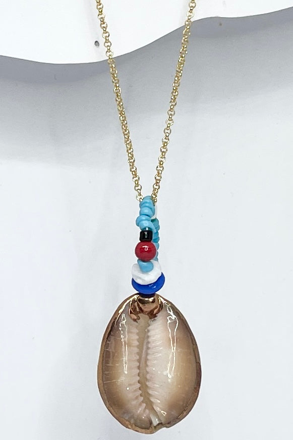 A pendant keepsake made with a cowrie shell which hangs from a circlet of simple green and white village beads. Then suspended from a chain.