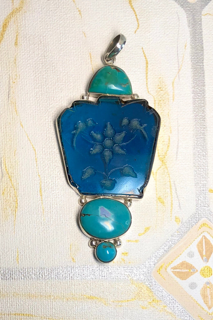 Echo Intaglio Blue Pendant is a mystical and historical pendant featuring Unsymmetrical cut turquoise glass intaglio and each piece has been set in silver.