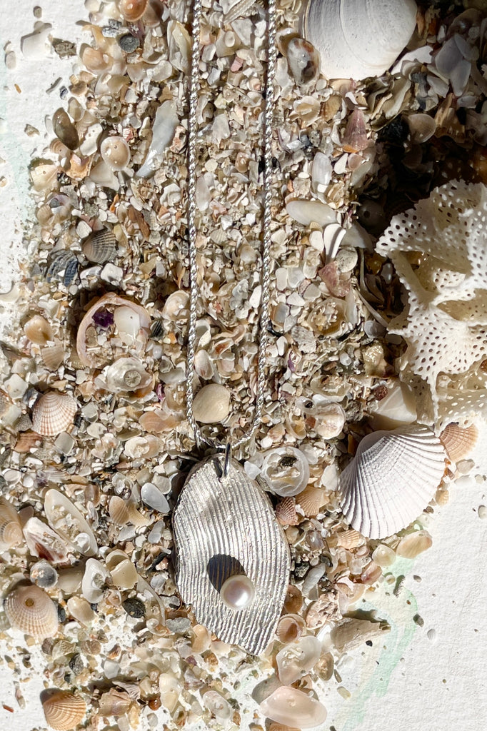 The pendant is solid silver, it is cast from the surface of a Pippi shell, and designed to carry the pearl bubble on the waves reaching the shore.