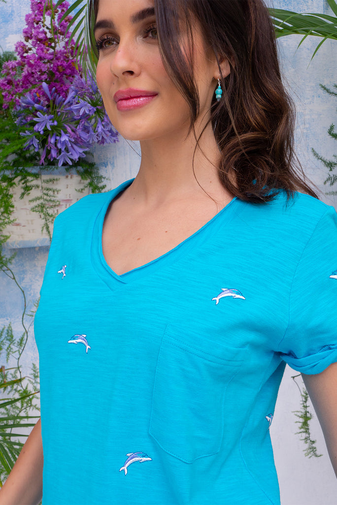 The Aurora T-Shirt Blue Dolphin is a sky blue, relaxed fit, t-shirt with embroidered dolphins all over. The shirt features a raw edged v-neck, front breast pocket, side spilt and rolled sleeve. Made from Knit 100% cotton.
