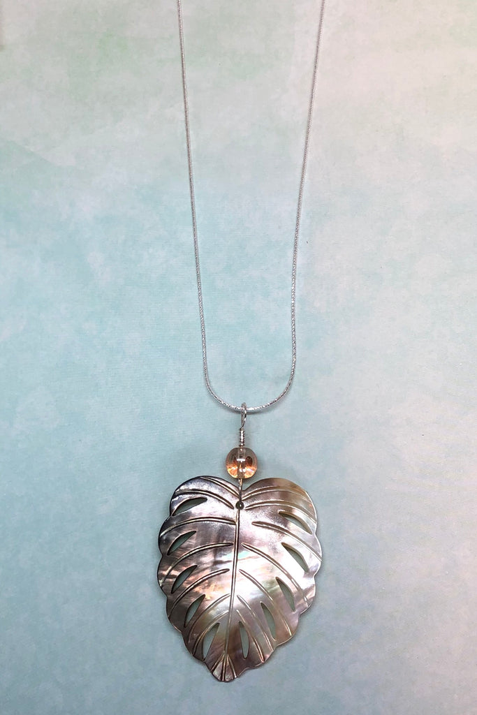 The gorgeous leaf pendant in gold and silvery bronze Mother of Pearl has been hand cut and polished. At the top there is an iridescent crystal bead.