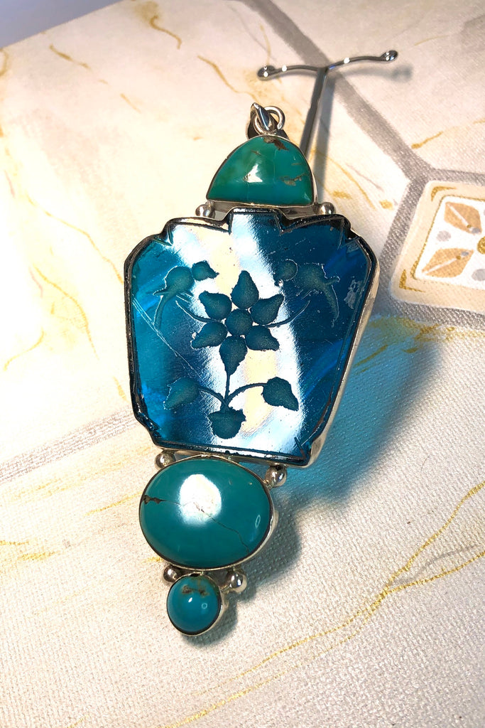 Echo Intaglio Blue Pendant is a mystical and historical pendant featuring Unsymmetrical cut turquoise glass intaglio and each piece has been set in silver.