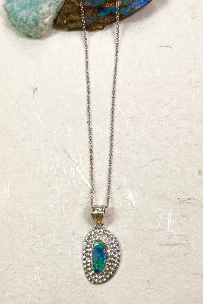 The Australian opal pendant is shaped into an abstract shape with a polished frame
