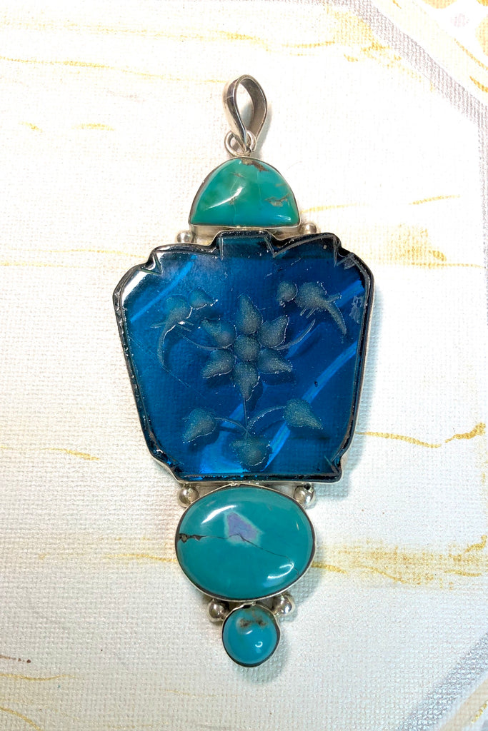 Echo Intaglio Blue Pendant is a mystical and historical pendant featuring Unsymmetrical cut turquoise glass intaglio and each piece has been set in silver.