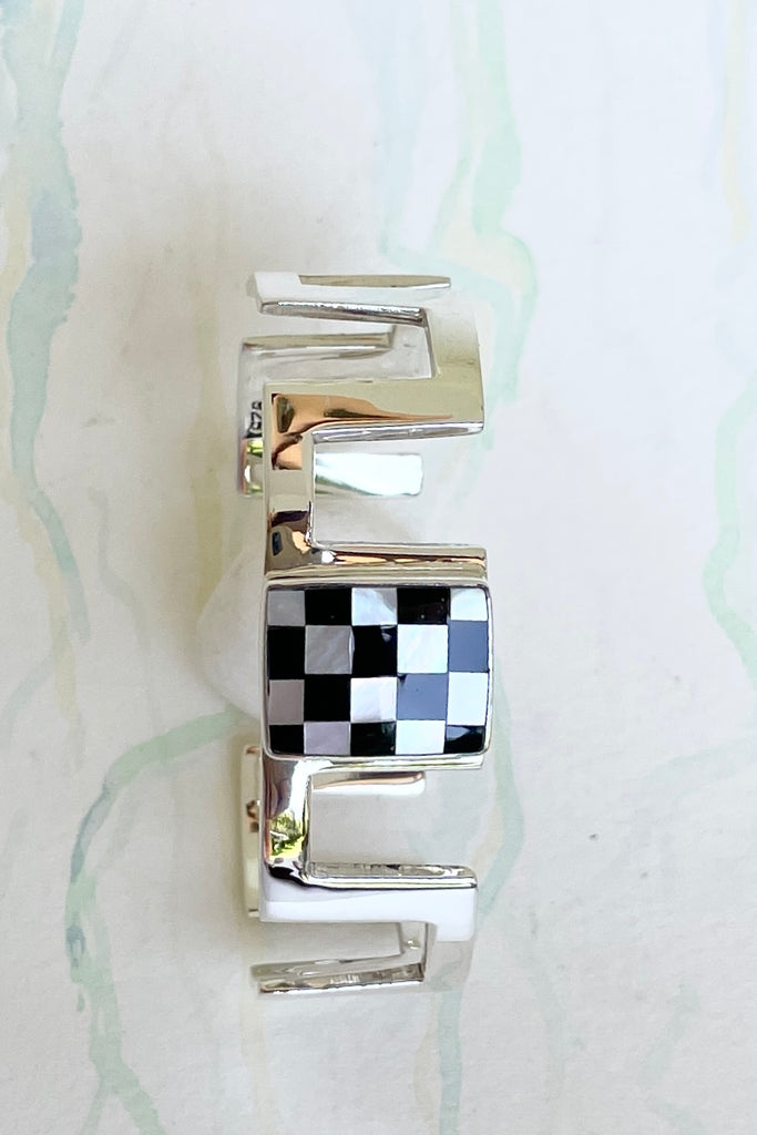 Very cool and sophisticated, this 925 silver cuff bracelet rocks the modern retro cool. In a square geometric design featuring a centre square inlaid with mother of pearl and black enamel,