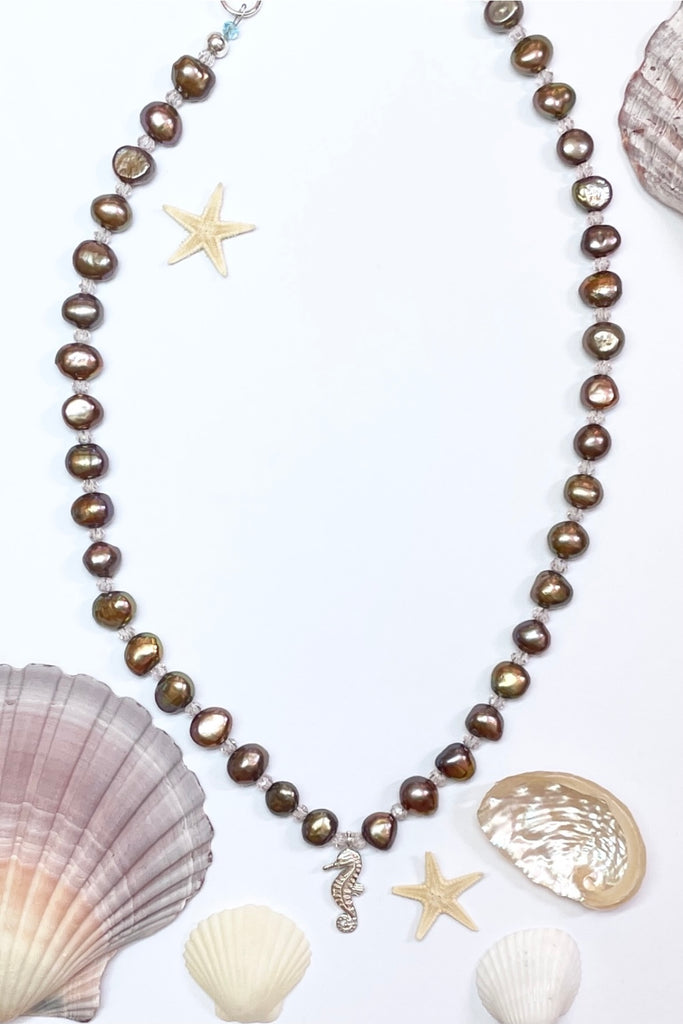 pearl necklace Cay Precious has golden cognac pearls interspaced with Swarovski crystals. There is a tiny silver seahorse as a centerpiece.