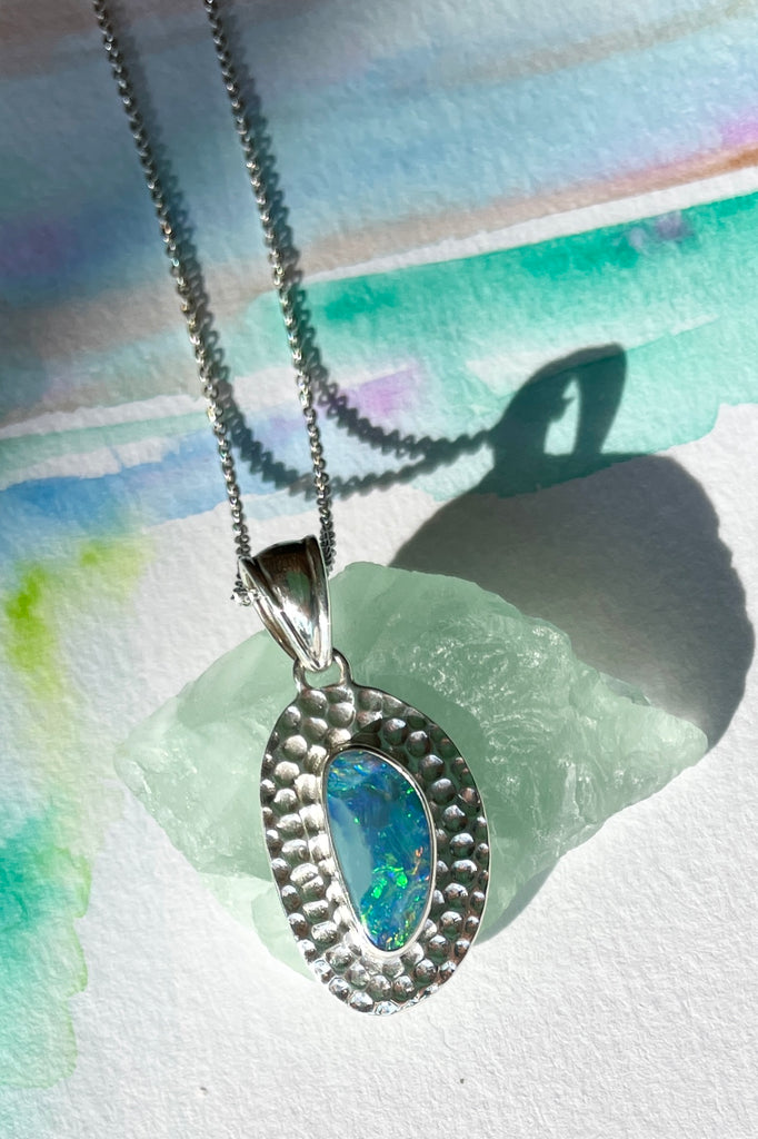 The Australian opal pendant is shaped into an abstract shape with a polished frame