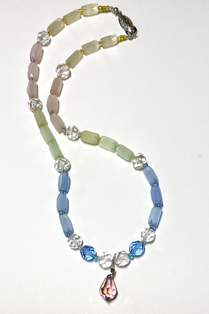 This beautiful necklace is made with vintage crystal beads in clear and a lovely faceted clear blue colour, and also has old Venetian glass beads in pale green pink and yellow. It also has a central pinky mauve droplet bead.