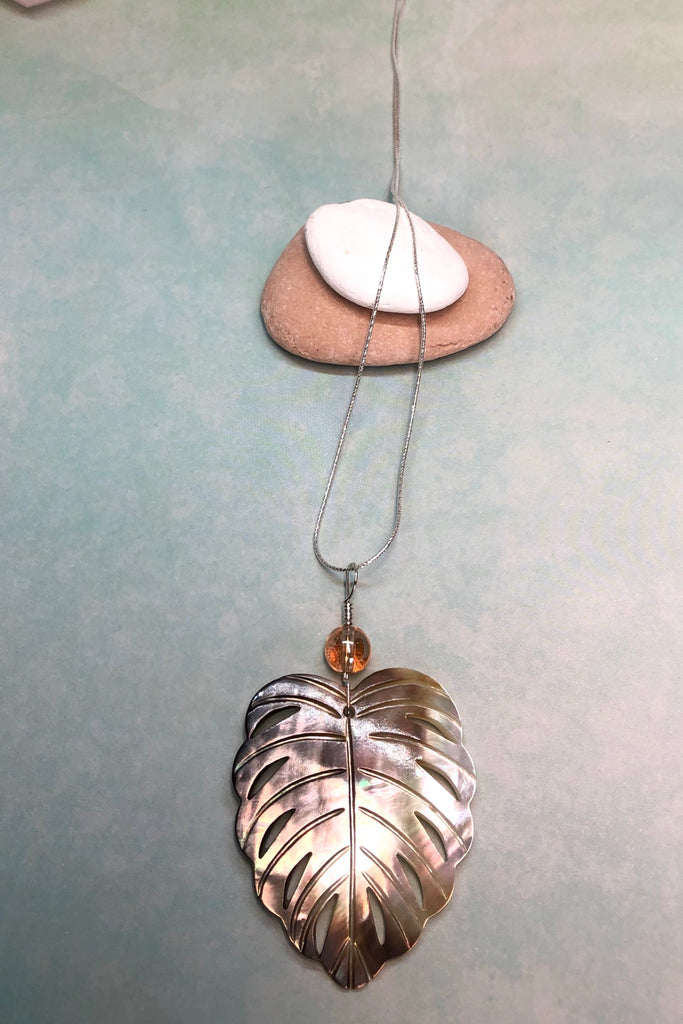 The gorgeous leaf pendant in gold and silvery bronze Mother of Pearl has been hand cut and polished. At the top there is an iridescent crystal bead.