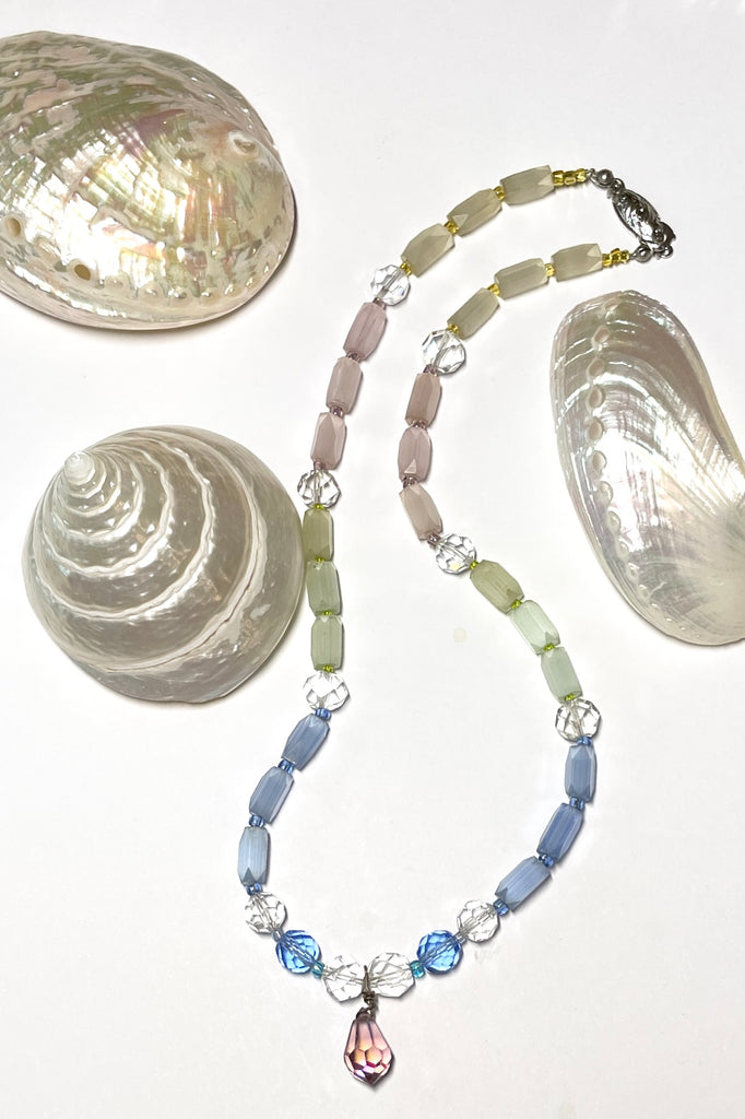 This beautiful necklace is made with vintage crystal beads in clear and a lovely faceted clear blue colour, and also has old Venetian glass beads in pale green pink and yellow. It also has a central pinky mauve droplet bead.