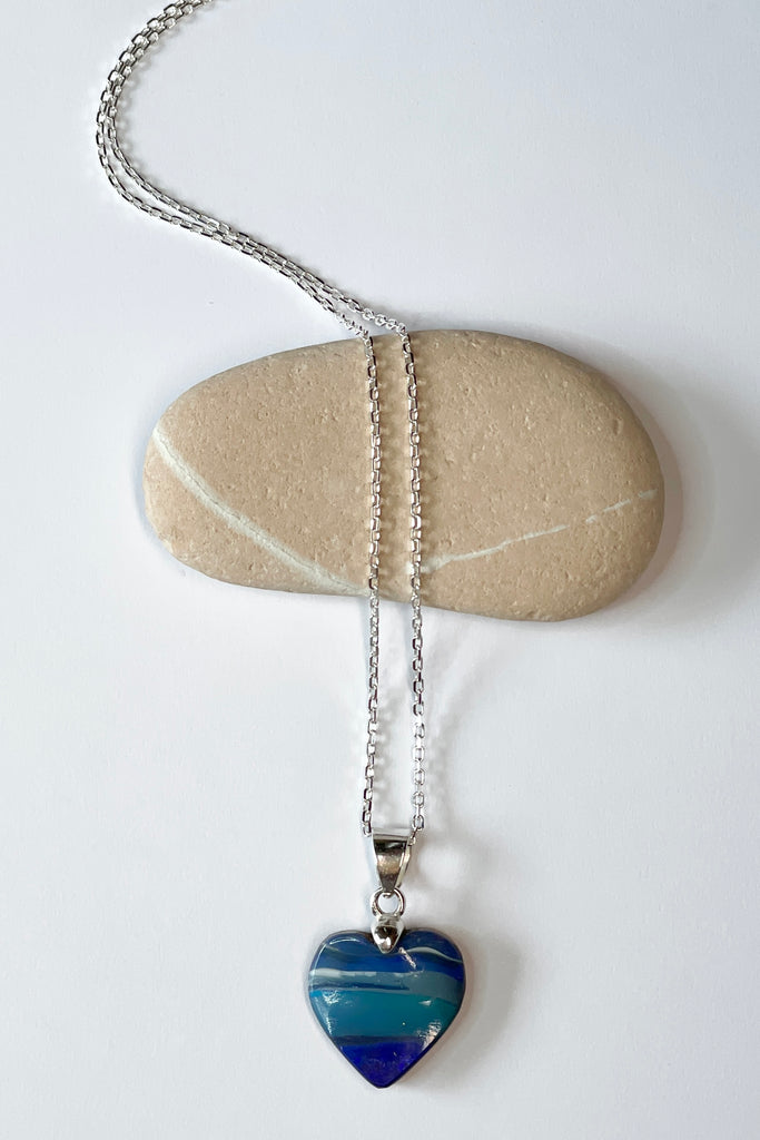 A blue boulder opal pendant There are lovely dark blue and teal blue stripes across the piece they are so well defined as to appear painted by nature.