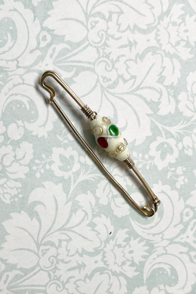 An interesting vintage tie pin with gold wire work around a white lamp work bead. 