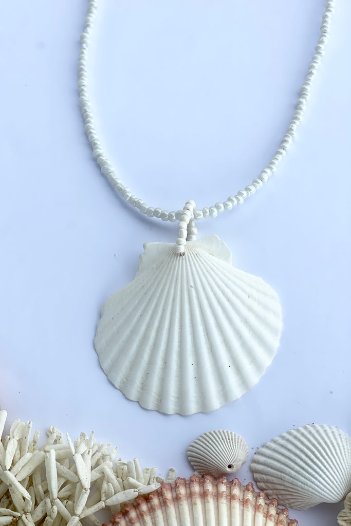 this gorgeous simple shell is almost pure white some have very pale pink markings, no two shells are ever alike,  strung on pearlescent white glass beads.