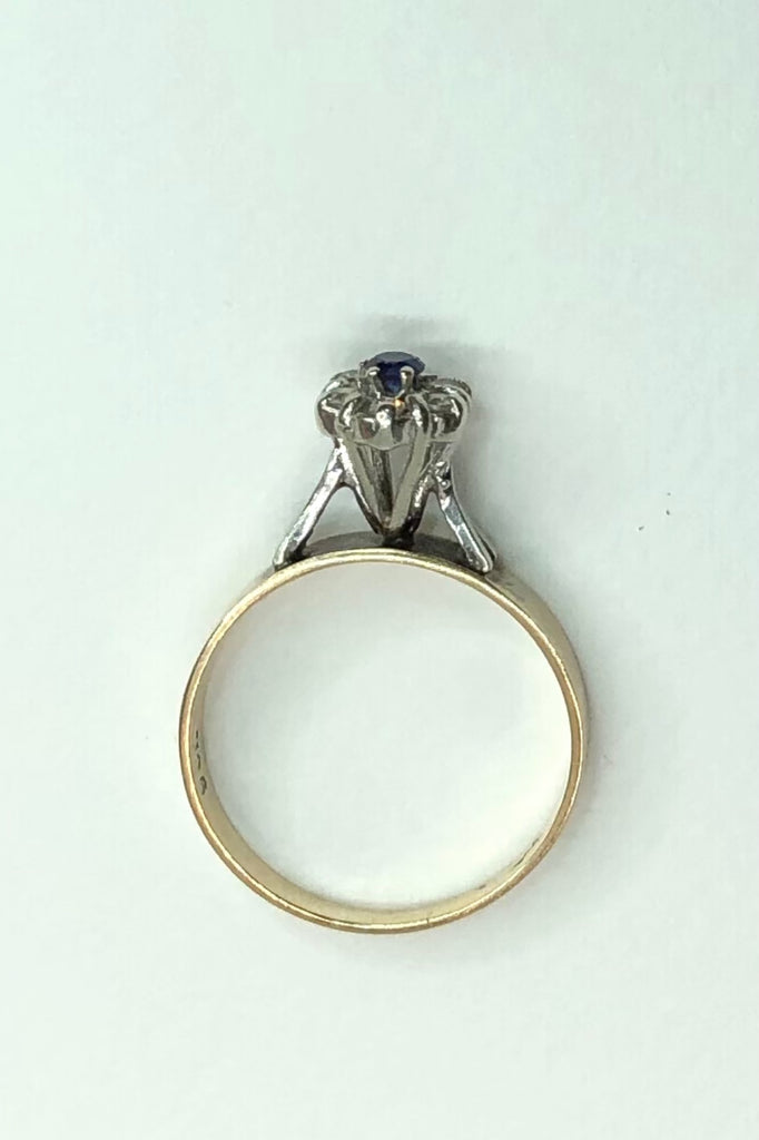 This Vintage ring features a very high setting, a small clear blue sapphire is halo set with six old cut white topaz. 