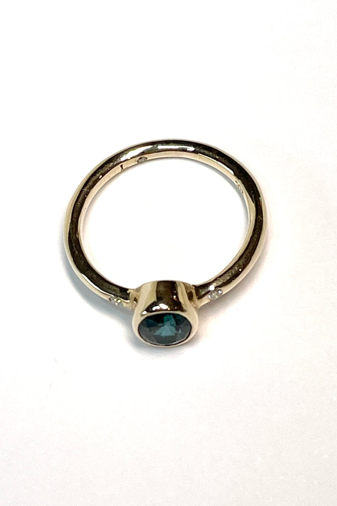 A beautiful simple ring designed to complement the lovely natural teal blue tourmaline gemstone set into the ring. The shank of the ring has a diamond on each side of the centre stone.