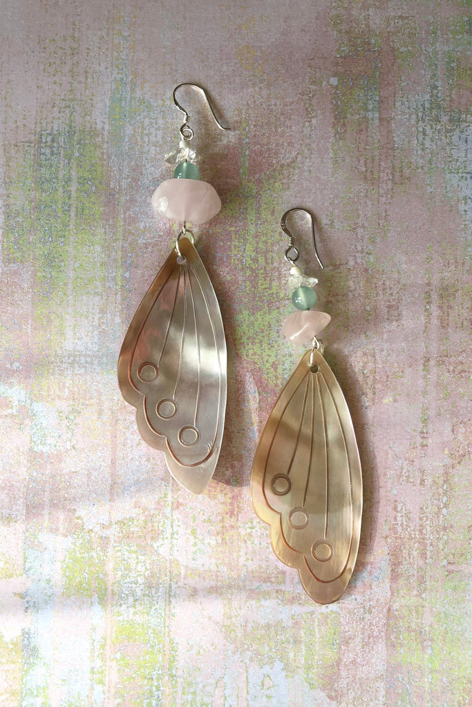 Serendipity Earrings Butterfly Wing Shell Pink are handmade exclusively for us. The gorgeous pale pink Mother of Pearl wing has been hand cut and polished. At the top there is a pebble of natural Rose Quartz, an Amazonite bead and a rock crystal bead.