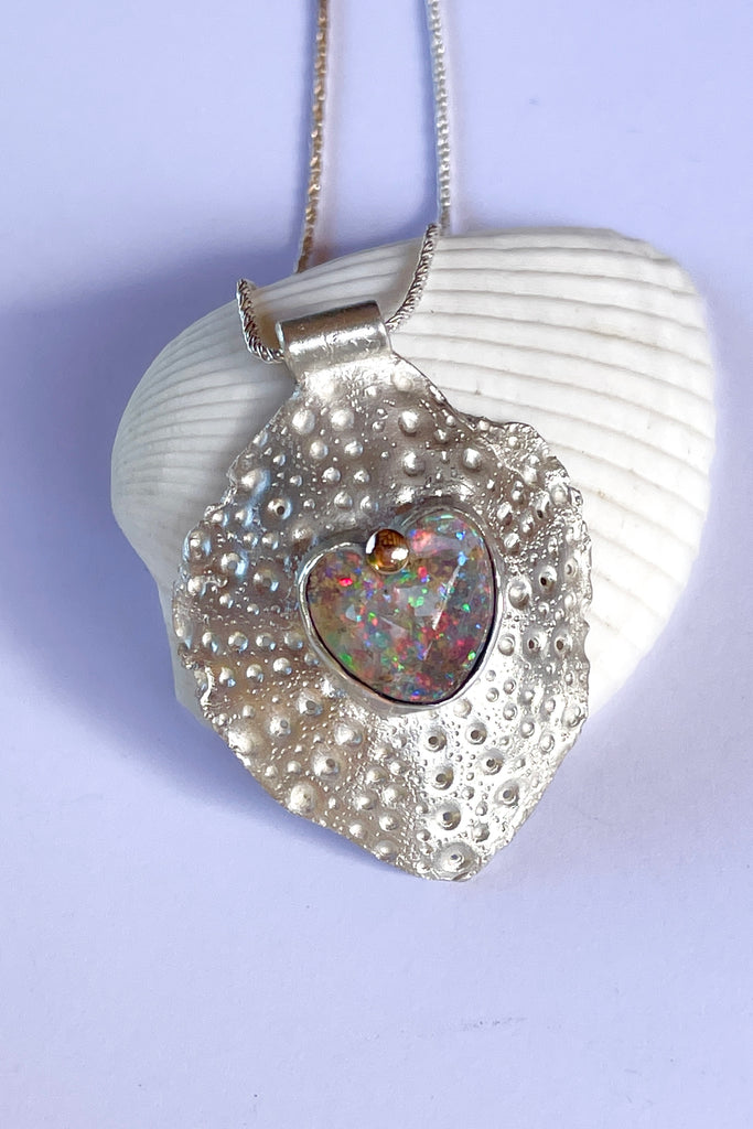 The heart opal centre piece is cut from natural solid Australian Opal. The silver is moulded from the shell of a sea urchin, then the opal is applied with the aid of a small gold dot of repurposed 18ctgold.