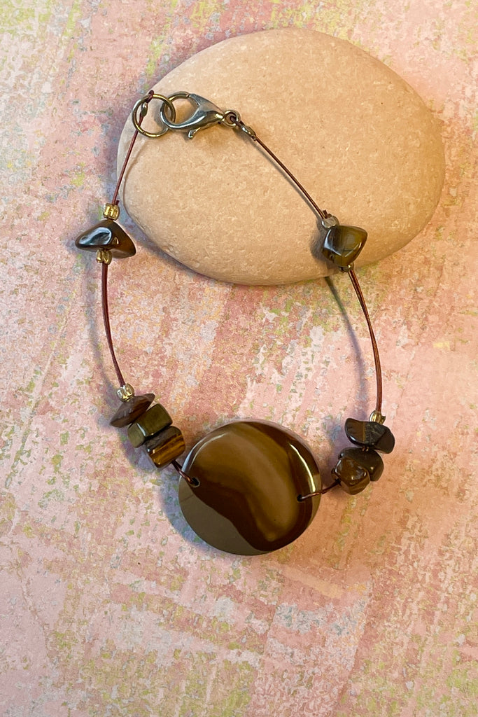 A handmade bangle with a centre piece of Agate stone which has been cut and polished by ROAM Ladies Lapidary Collective in Sakaraha, Madagascar. The band isTigers Eye chip beads. This collective was created with aid funds from the Australia