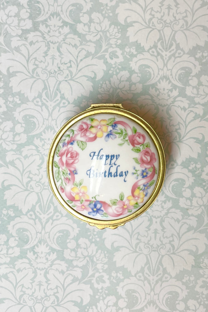 A pretty English bone china gift box, decorated with flowers it has a hinged lid. Happy Birthday box.