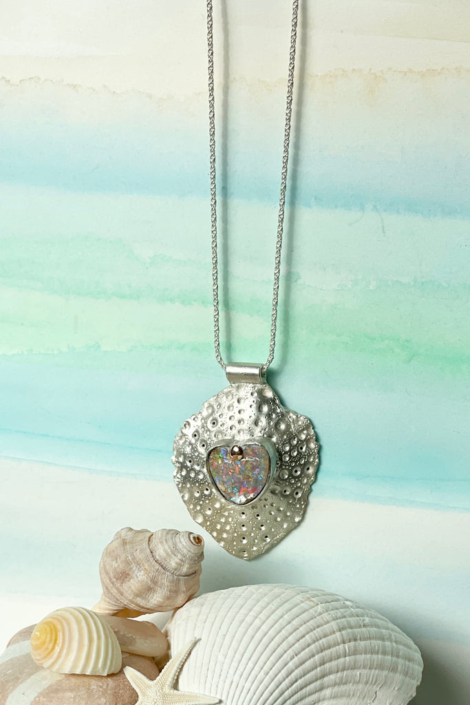   The heart opal centre piece is cut from natural solid Australian Opal. The silver is moulded from the shell of a sea urchin, then the opal is applied with the aid of a small gold dot of repurposed 18ctgold. The pendant is a one off designer piece, made for this opal heart. 