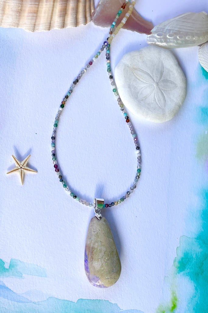This opal is a one off piece, a hand cut and shaped light matrix opal, there is a lovely pale mauve crystal cave on one side, the top surface shows a mysterious bright green sparkle under sunlight.