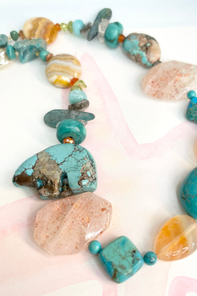 The necklace features a hand carved Zuni bears bought in Taos new Mexico. Stones are Natural Turquoise, Herkimer Diamond, Kyanite rough shards, Pearl, natural Sunstone, Strawberry Quartz, Banded Agate, Peridot and Labradorite .