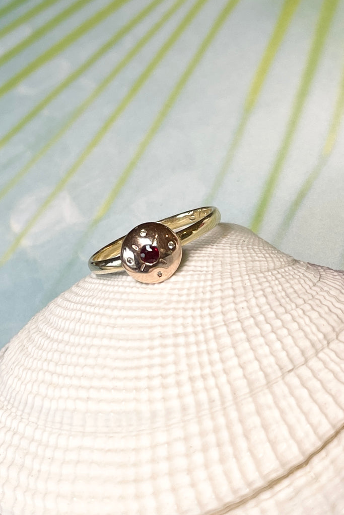 This Vintage diamond ring features a  central dark red garnet and four tiny diamonds. In 9ct gold band, the centre is in rose gold