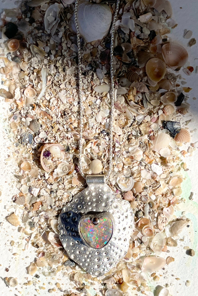 The heart opal centre piece is cut from natural solid Australian Opal. The silver is moulded from the shell of a sea urchin, then the opal is applied with the aid of a small gold dot of repurposed 18ctgold.