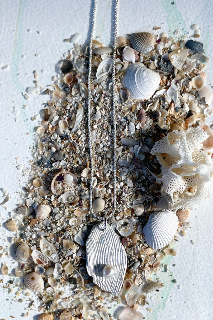The pendant is solid silver, it is cast from the surface of a Pippi shell, and designed to carry the pearl bubble on the waves reaching the shore.