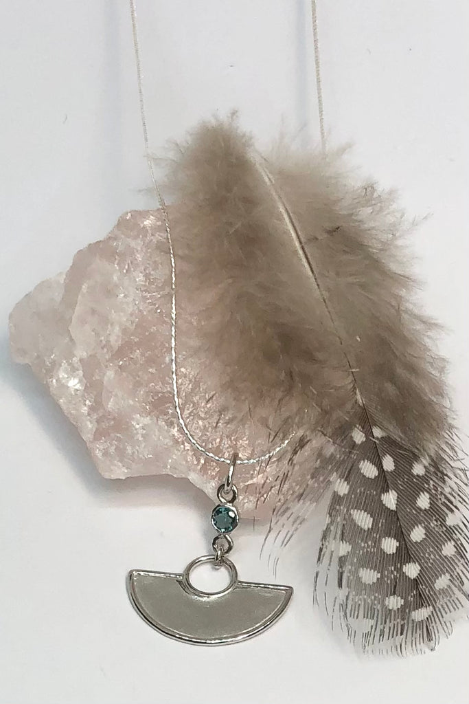 A stunning African Style 925 silver pendant with a Tourmaline Shard which hangs perfectly through a silver circle. The intense blue Tourmaline was sourced ethically from miners in Nigeria,