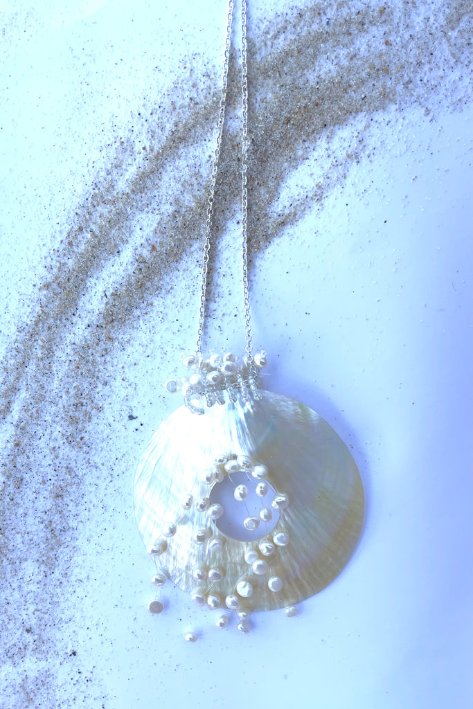 An iridescent circle of beautiful golden Mother of Pearl shell, hung with pearls on a simple silvery chain.