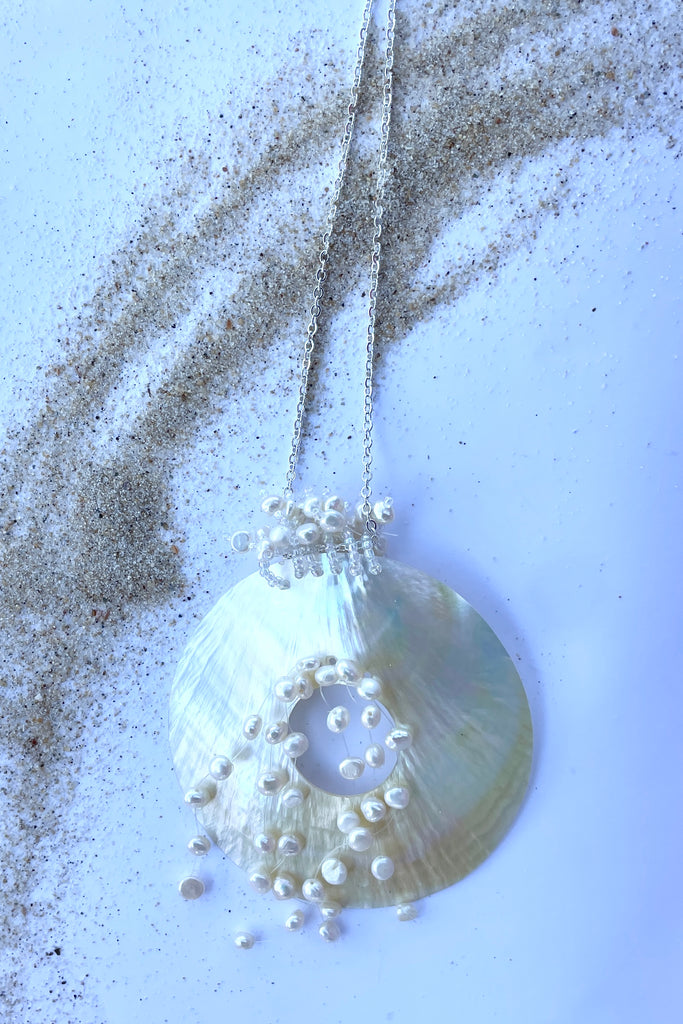 An iridescent circle of beautiful golden Mother of Pearl shell, hung with pearls on a simple silvery chain.